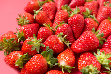 Ripe juicy orgaic strawberries on a red background.