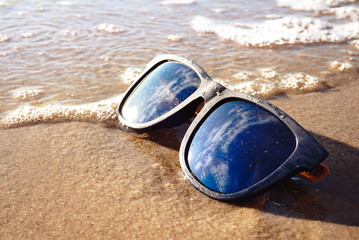 Fototapeta na wymiar Blue sunglasses lay on the beach