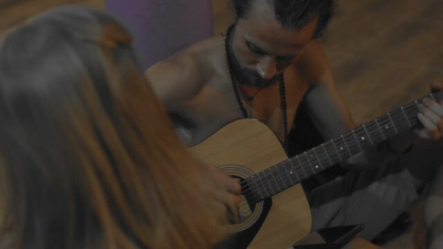 Hippie musician performing outdoors close up slow motion. Bearded man playing guitar on street side view. Alternative culture lifestyle. Travel leisure time summertime.