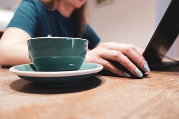 Woman using laptop with Cup of coffee, side view