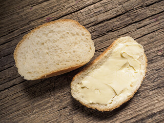 Slice of white bread with butter on a wooden board. Top view. Close-up