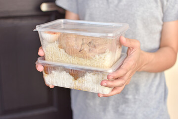 Lunch box with food in the hands.
