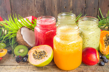 Fototapeta na wymiar Assorted different fruit smoothies and juices with tropical fresh fruits and berries. Clean eating, healthy lifestyle, diet and vitamin drink beverages concept. Top view flatlay