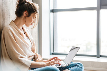 Image of woman working with laptop while sitting on floor