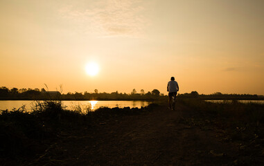Fototapeta premium The man biking alone on the clay road. He want to avoid the traffic in the alphalt road as it risk to get the spread of COVID-19. This is new normal concept