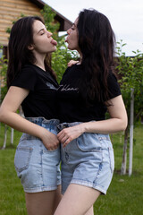 Two young brunette women in a black T-shirt and denim shorts hugging. Sisters, girlfriends. family and friendship concept. High quality photo