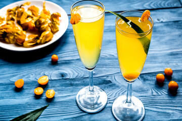 cocktail with physalis in glass on wooden background