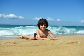 Child playing in sand on the beach. Cheerful boy play on send on summer holiday