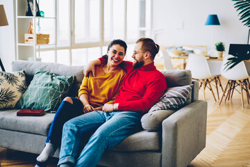 Obraz premium Emotional romantic couple feeling happiness resting in cozy home interior,young marriage satisfied with getting new apartments for living sitting at comfortable sofa