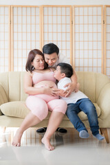 An Asian pregnant woman and her family sat on the sofa
