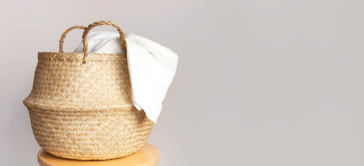 Straw wicker basket and white natural cotton fabric, towel on gray background. Fashionable bamboo...