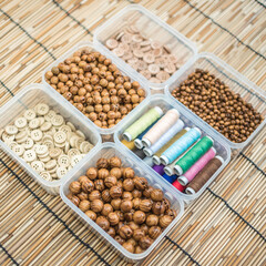 Wooden Beads and Buttons, Natural Craft Supplies, Colorful Sewing Thread on Bamboo Background