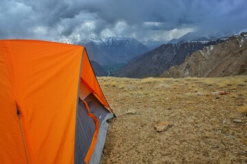 orange color tent being set up by trekkers for night stay in ladakh