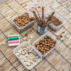 Wooden Beads and Buttons, Natural Craft Supplies, Colorful Sewing Thread on Bamboo Background