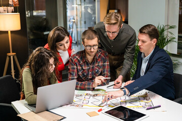 Team Of Architects Working On Project Paper Blueprint. Group Of Modern Business People In Casual Wear Discussing Architectural Designs While Sitting In The Creative Office. - obrazy, fototapety, plakaty