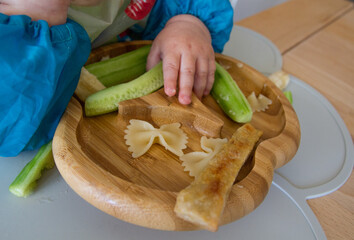 Plate of food for baby nutrition BLW (baby-led weaning) with baby hands grabbing for food 