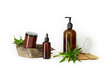 dark brown bottles cosmetics no label on natural dark stone with water lilies green leaves and white towel on white background isolated