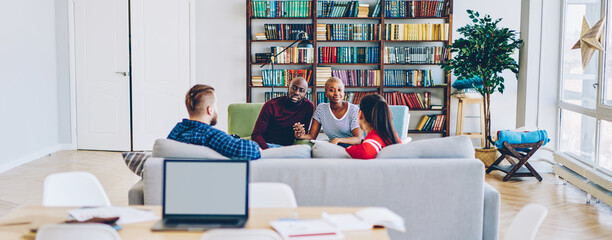 Couples having meeting in hostel communicating in modern designer room with bookshelves, young...