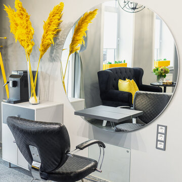 Interior of modern beauty and hairdresser salon with armchair and mirror in yellow and black tones.