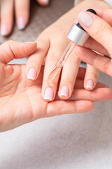 Professional manicurist pouring oil on nails french manicure of woman in beauty salon.
