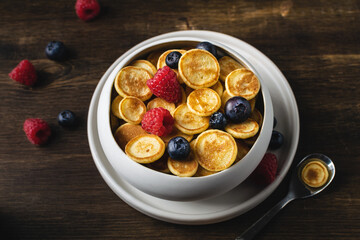Fototapeta na wymiar Trendy homemade breakfast, pancake cereal, mini pancakes with berries,