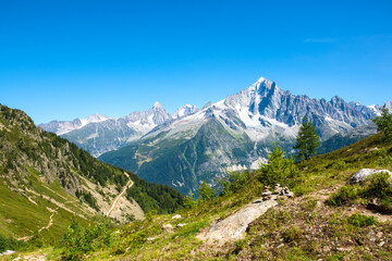 Alpine landscape with Mont Blanc mountains at summer from Plan Praz. Pyramid from stacked stones on a trail. France nature tourism background. Hiking, eco-planet concept.