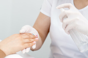 Manicurist is applying spray on client hand. Manicure disinfection with spray.