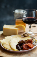 cheese snack with honey fruit and red wine on a wooden stand