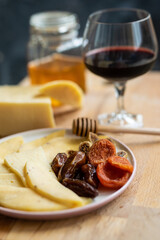 cheese snack with honey fruit and red wine on a wooden stand