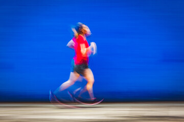 blurred image of woman jogging in a red shirt against blue background - healthy lifestyle