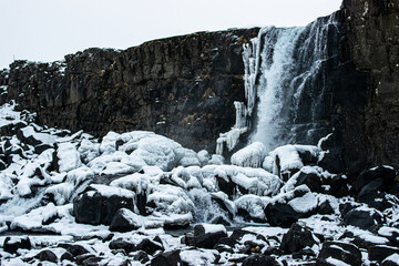 Fototapeta na wymiar Photo of an impressive cascade surrounded by snow in Iceland