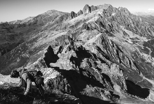 Alpinist (unrecognizable dark silhouette) preparing to descend from Le Brevent mountain in summer and beautiful Alpine landscape at background. Chamonix, Mont Blanc, Savoie, France. Black white photo.