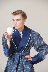 young man in blue coat is enjoying coffee