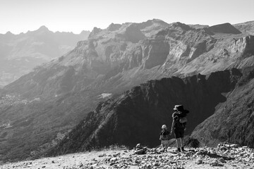 Family summer holidays in mountains. Father and his little son admire Alps mountain landscape. Back view. Active vacation with kid, fathers day concepts. France tourism background. Black white photo.