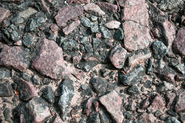 grained  asphalt, from under which stones can be seen macro