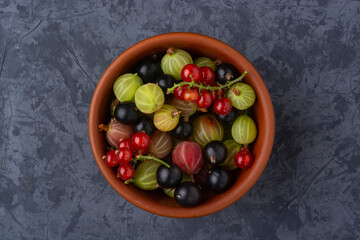 Currant and gooseberry berries in a ceramic bowl. View from above.
