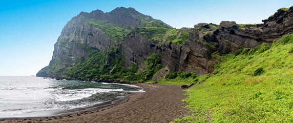 panoramic view of the Black pebble beach, cliff volcano of seongsan Ilchulbong on the jeju island.