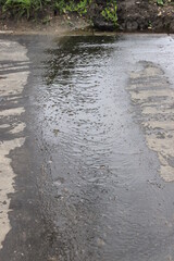 Water flows on asphalt. Russia.