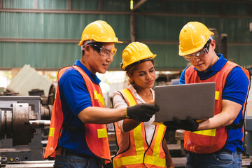 Group of creative asian technician engineer and engineer woman dark skin wearing uniform and safety helmet under inspection and checking production process on factory station by laptop computer.