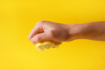 Hand crushes a piece of fresh lemon