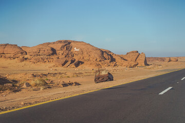Wrecked car after accident along highway surrounded by sand desert