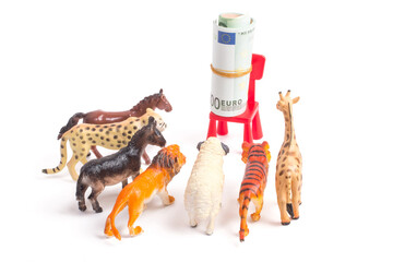 Toy plastic figurines of animals on white isolated background. Crowd of animals in front of a bundle of money. The concept of the desire to make money. People love money more than anything.