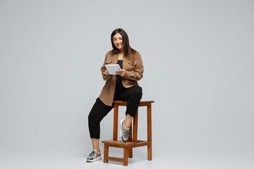 Obraz premium Fashionable, stylish. Young woman in casual wear on gray background. Bodypositive character, feminism, loving herself, beauty concept. Plus size businesswoman scrolling tablet. Inclusion, diversity.