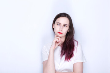 Young woman with red lipstick looks thoughtfully to side. Copy space
