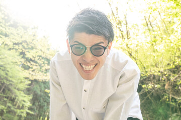東京の田舎にて、若い日本人青年男性がカメラ目線でにこやかに笑っている様子