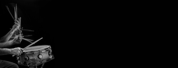 Drummer's hands and drumsticks in motion, while striking a snare drum.