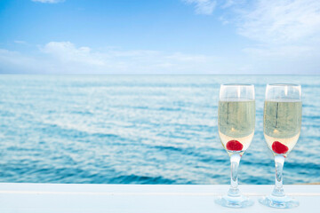 Two champagne glasses near the sea. Space for text