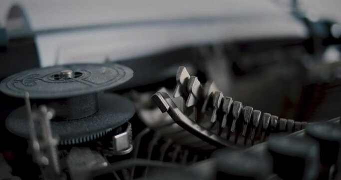 Close-up ribbon of an old vintage typewriter with metal bolts writing text in background - Slow Motion