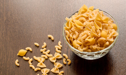 Raw yellow pasta scattered on a dark table. Random pattern with copy space.