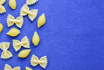 Raw yellow pasta on a blue background. Random pattern with copy space. View from above.
